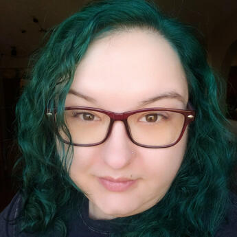 A straight-on photo of Katina's face, framed by her teal hair.